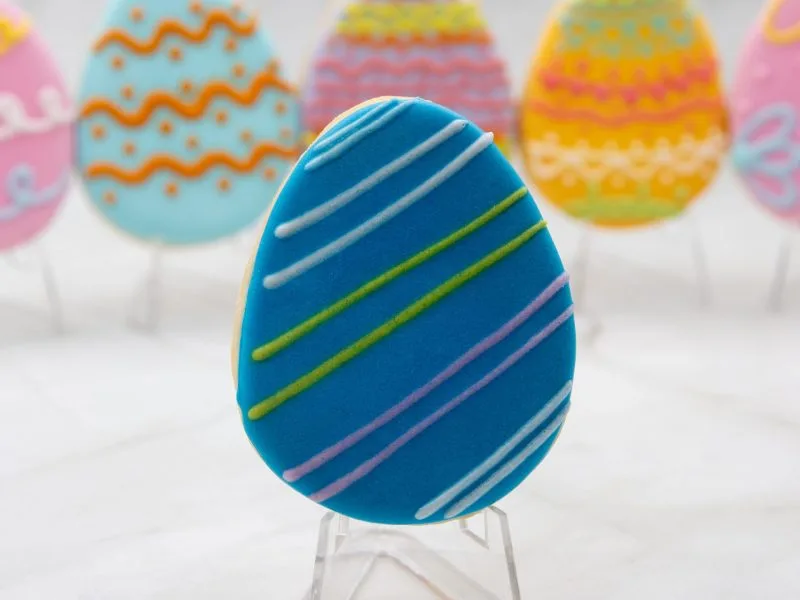 Close-up of an individual Easter Egg Wonderland Cookie with blue and green swirl patterns decorated in royal icing.