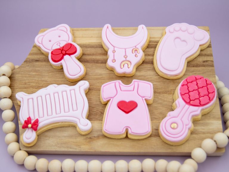 Baby shower cookie set styled with pink decorations and girl-themed party props