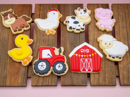 Flat lay of 8 farm animal cookies on wood board