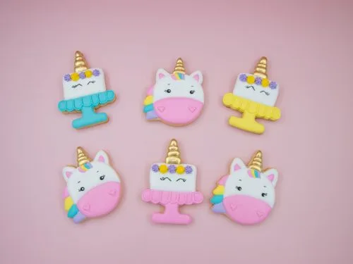 Flat lay of unicorn head and birthday cake cookies on pink background