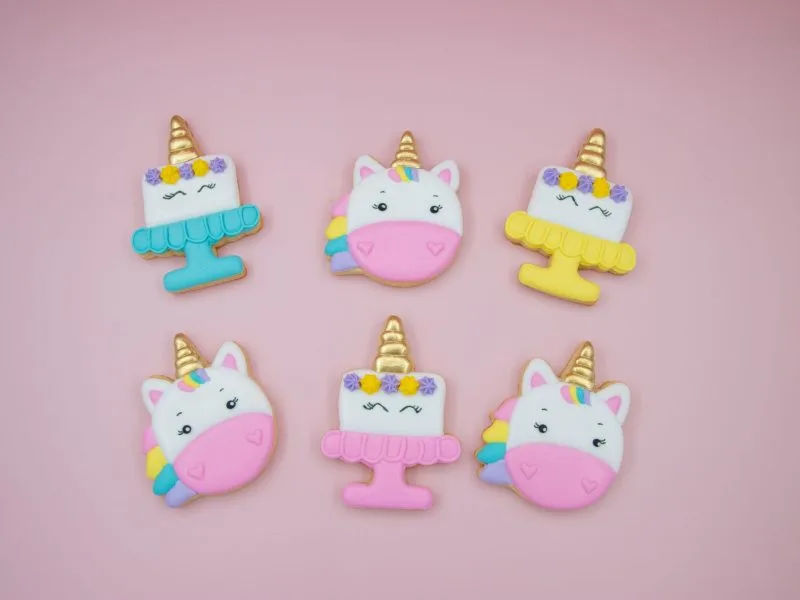 Flat lay of unicorn head and birthday cake cookies on pink background