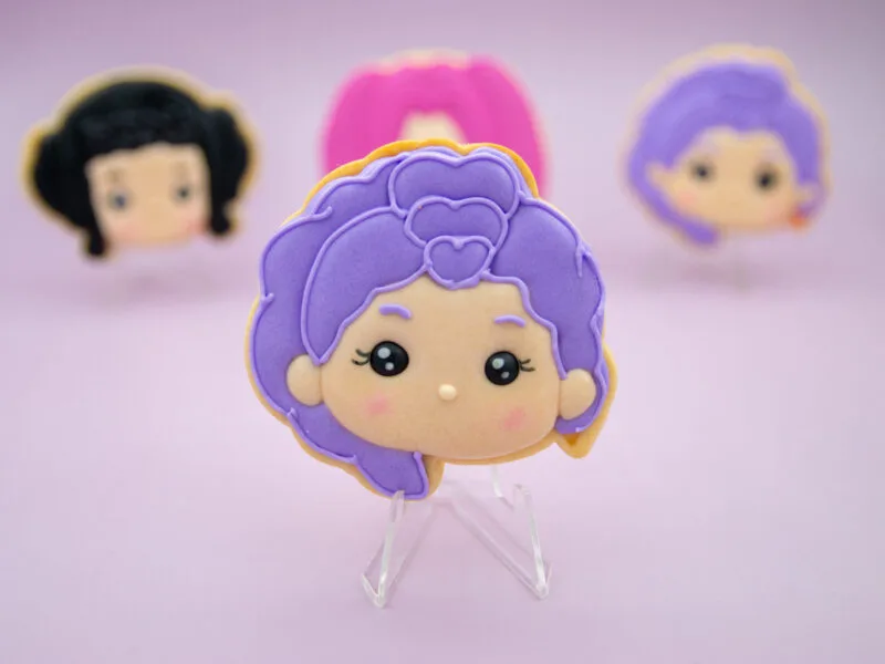 Rumi Huntrix character cookie with with purple hair and royal icing