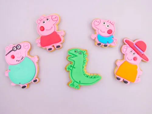 Peppa Pig Family Cookies flat lay with fondant family character designs and green dinosaur cookie