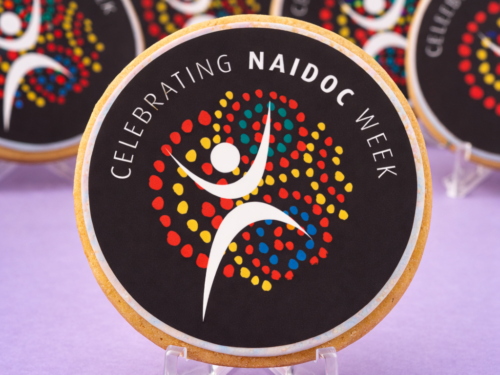 Close up of Celebrating NAIDOC Week Cookie with colourful edible print artwork on black fondant