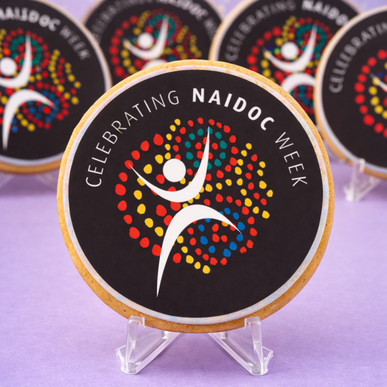 Close up of Celebrating NAIDOC Week Cookie with colourful edible print artwork on black fondant