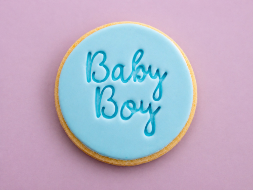 Flat lay baby boy cookies with smooth blue fondant and embossed text