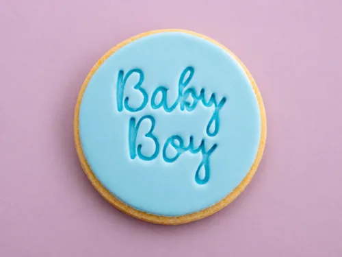 Flat lay baby boy cookies with smooth blue fondant and embossed text