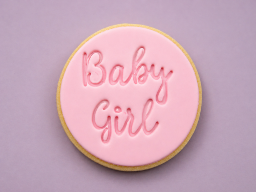 Flat lay baby girl cookies with smooth pink fondant and embossed text
