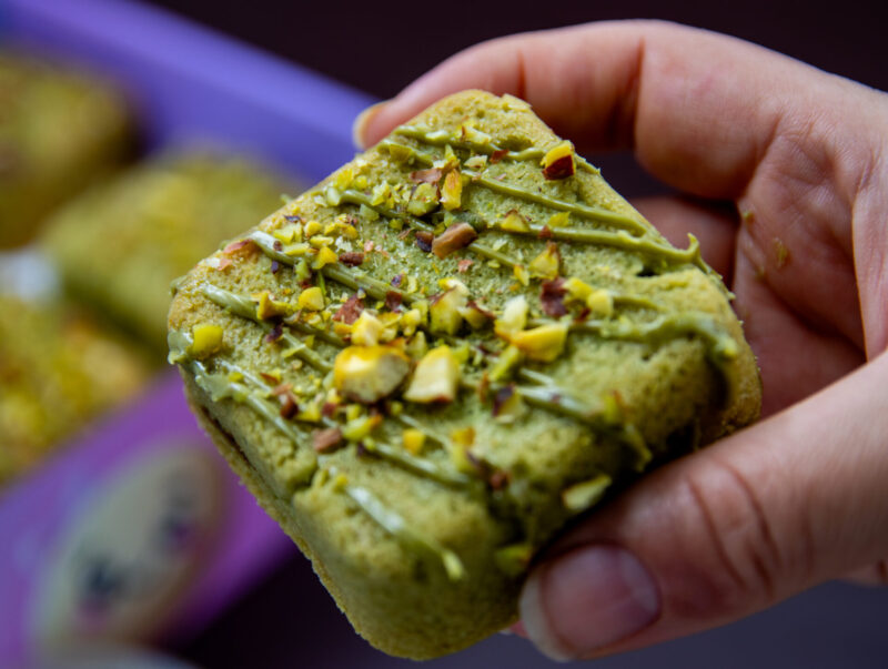 Hand holding Pistachio Cream Cookie Cube topped with pistachio pieces