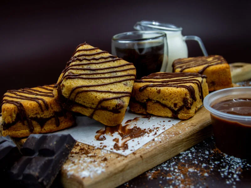 Chocolate Chip Cookie Cubes with chocolate drizzle and chocolate dip on wooden board
